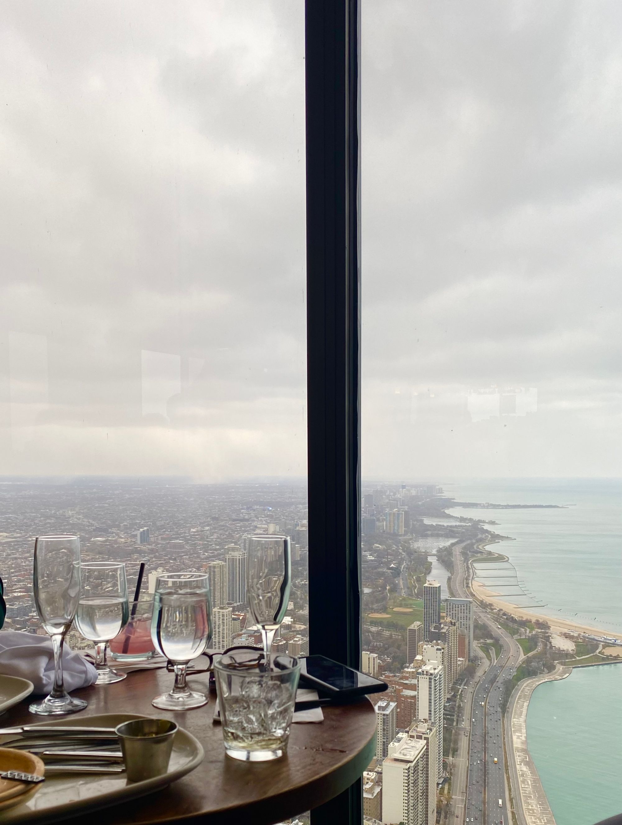 view of chicago from the 96th floor of the old sears tower, with a table and glasses in the foreground